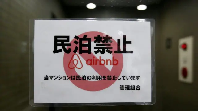 FILE PHOTO: A sign communicating the ban on using the apartment building as Airbnb service by the building management is attached to the building"s front door in Tokyo, Japan