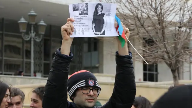 Молодой человек с распечатанным фото и текстом поздравления с 8 марта