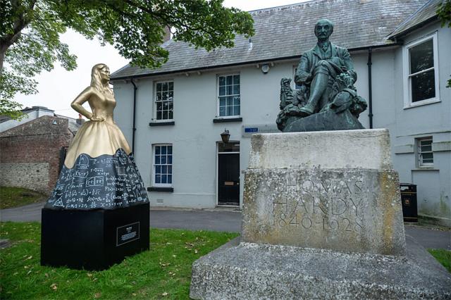 Mary em frente à estátua de seu irmão, o escritor Thomas Hardy, em Dorchester, na Inglaterra