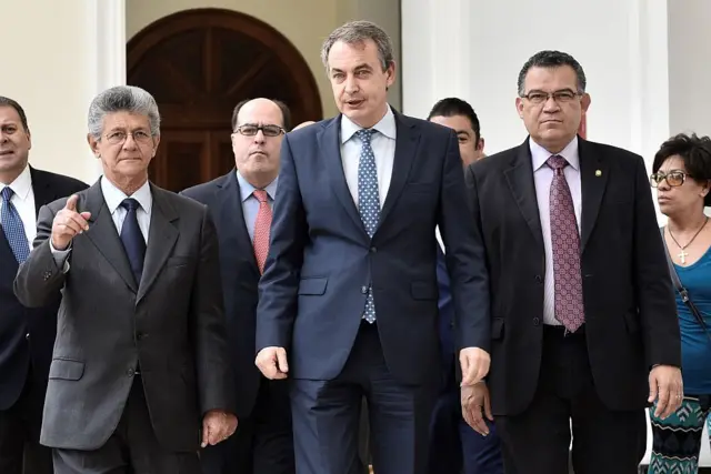 Henry Ramos Allup, Julio Borges, Enrique Márquezy Zapatero caminan uno al lado del otro, todos vestidos con traje de chaqueta y corbata.