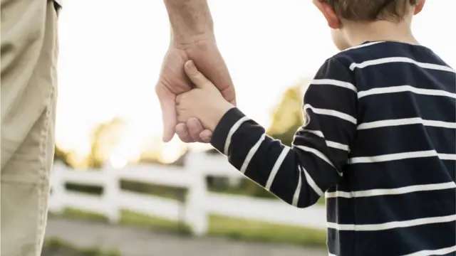 Pai caminhandoapostas sportingbetmãos dadas com o filho