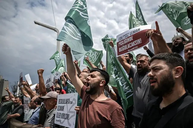 Bir grup eylemci slogan atarak dergiyi protesto ediyor. Bir eylemcinin elindeki dövizde "Edepsiz leman, pisliğinde boğulacaksınız" yazıyor. 