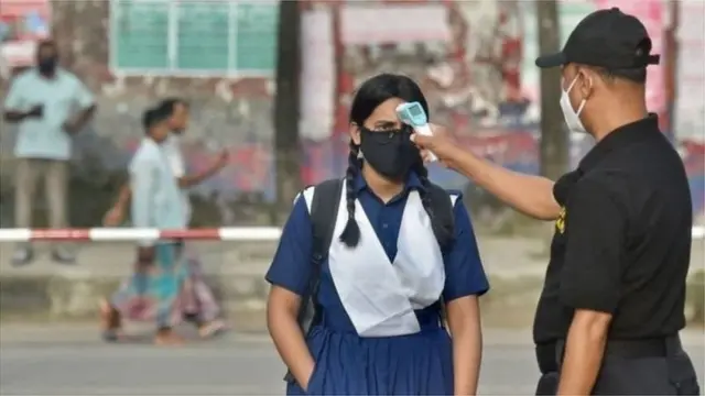 ঢাকার একজন শিক্ষার্থীর তাপমাত্রা মাপা হচ্ছে