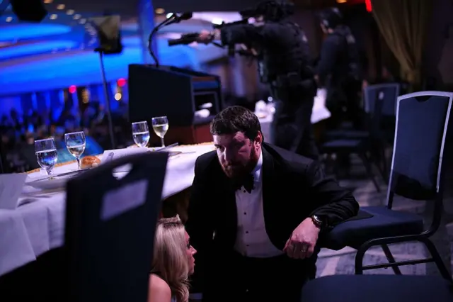 Женщина прячется под столом, рядом с ней агент безопасности