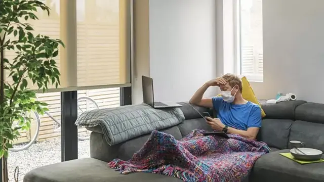 Un homme allongé sur un fauteuil recouvert d'une couverture