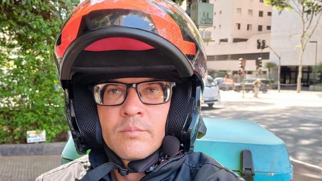 De capacete, Rodrigo Silva tira selfie durante trabalho como entregador em São Paulo