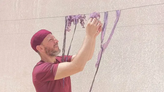 Mohammed Ghassen Nouira colgando tiras de tela teñida