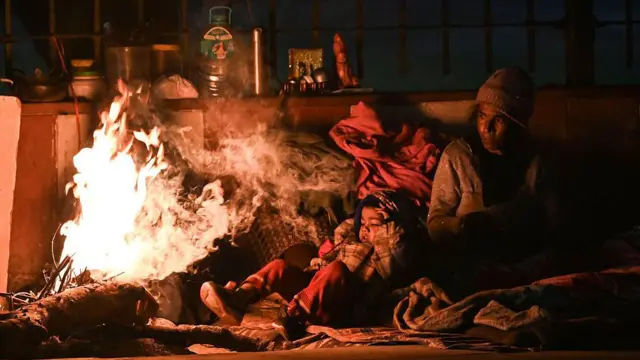 ၂၀၂၆ ခုနှစ် ဇန်နဝါရီလ ၁၀ ရက်နေ့ မနက်လင်းအားကြီးအချိန် ဒေလီမြို့က နီဇာမတ်ဒင် ရပ်ကွက်မှာ ဆွယ်တာနဲ့ ဦးထုတ် ဝတ်ထားတဲ့ အမျိုးသမီးတစ်ဦး ကလေးကို ပေါင်ပေါ်တင်ရင်း မီးပုံရှေ့ မီးလှုံနေပုံ