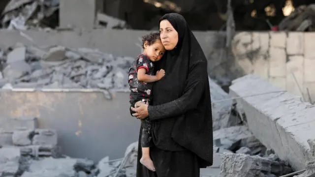 Filistinli bir anneyle çocuğu yıkık binaların önünde 