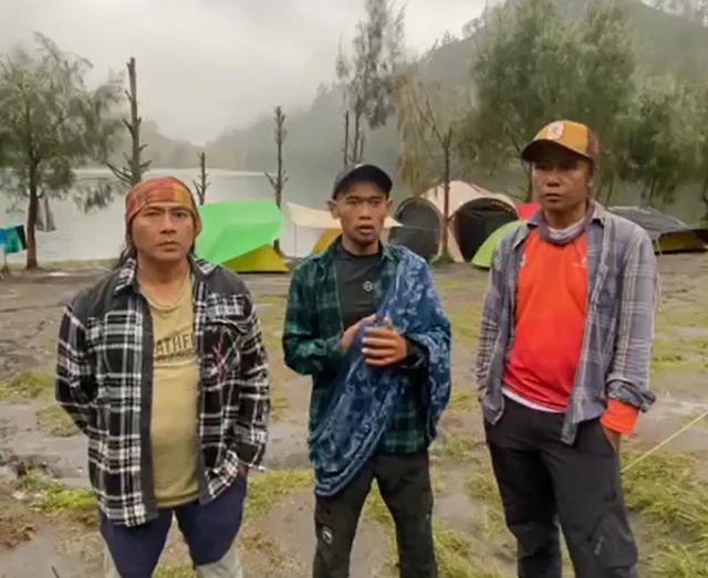 Tiga pria sedang berada di area perkemahan.