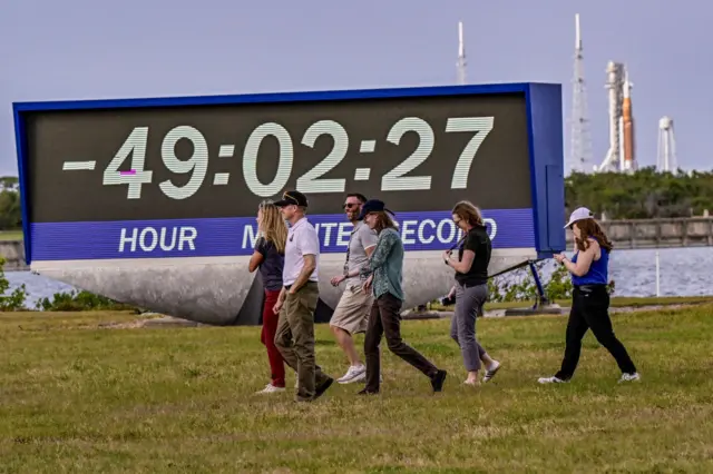 ABD'nin Florida eyaletindeki Cape Canaveral'da bulunan Kennedy Uzay Merkezi'nde, 30 Mart 2026'da gerçekleşmesi planlanan Artemis II görevinin fırlatılması için hazırlıklar devam ederken, medya mensupları basın alanındaki geri sayım saatinin önünden geçiyor.