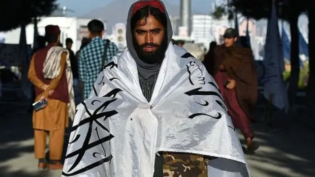 Man with Taliban flag wrapped around him