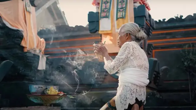 سيدة مسنة تجلس على ركبتيها خلال طقوس الصلاة بمهرجان غالونغان في إندونيسيا