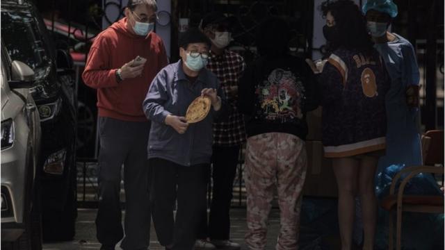 人們在中國上海的一個被封鎖的住宅社區裏領取麵包等口糧。