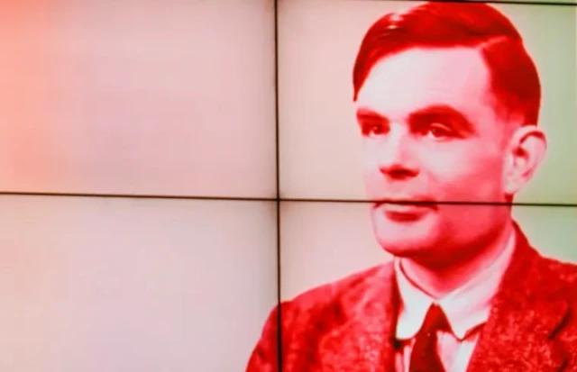 Imagem do cientista Alan Turing em um telão na cor vermelha