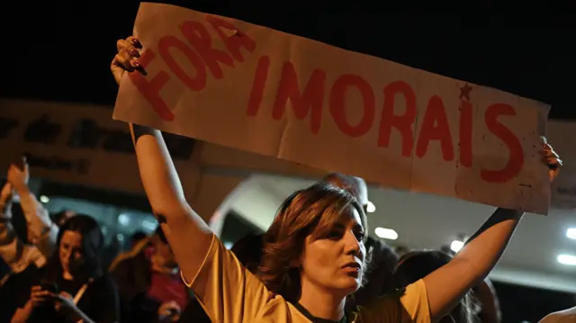 Uma apoiadora de Bolsonaro segura um cartaz escrito "fora imorais" em frente à casa do ex-presidente em Brasília nesta segunda.