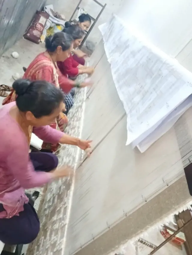 एउटा गलैँचा कारखानामा श्रमिकहरू काम गर्दै