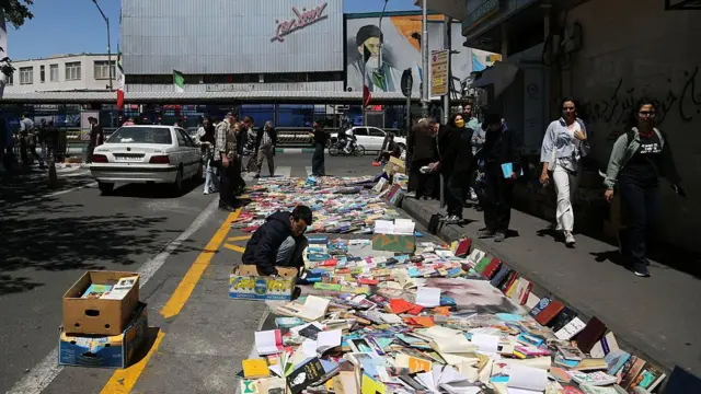 Книготорговец выкладывает сотни книг на обочине дороги в Тегеране