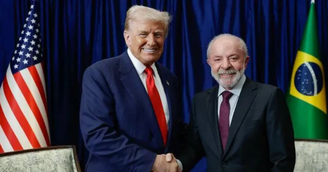Foto mostra Donald Trump à esquerda e Lula à direita apertando as mãos em uma sala com as bandeiras dos Estados Unidos e do Brasil ao fundo