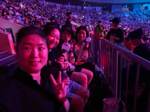 아미들이 한 공연장 안에서 포즈를 취하며 사진을 찍고 있다