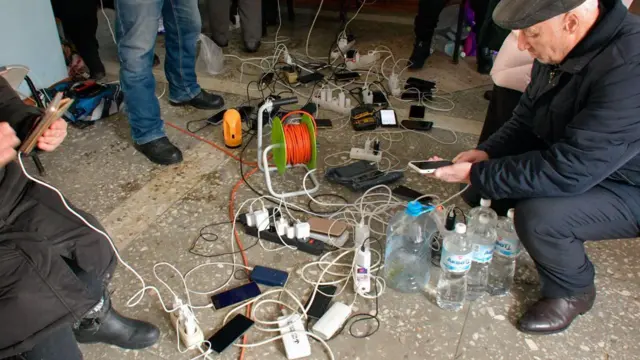 Жители Белореченского района заряжают телефоны в центре временного размещения: на полу розетки, телефоны, бутылки с водой