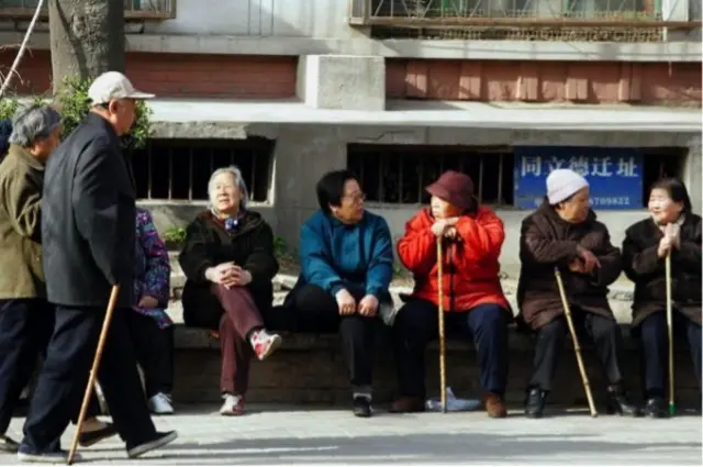 Plusieurs femmes âgées assises sur un banc discutent
