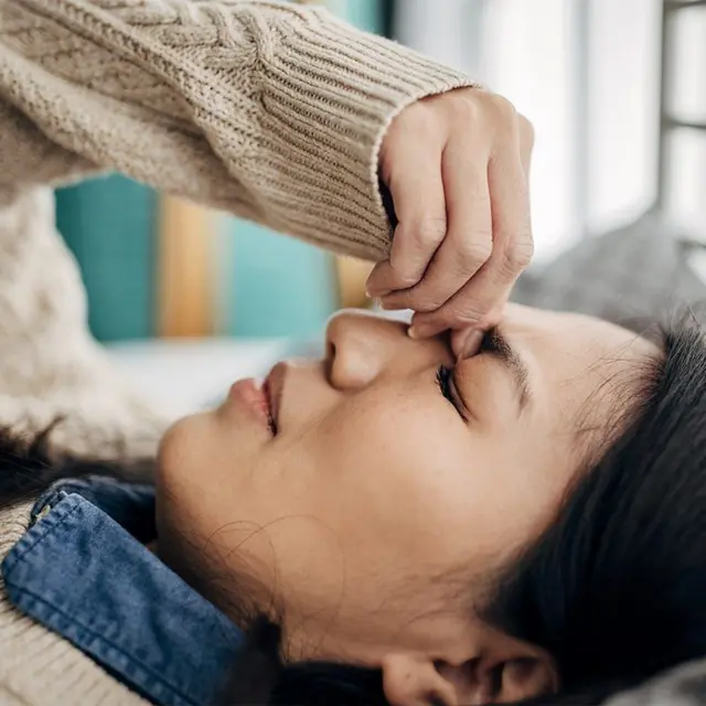 Mulher deitada com os olhos fechados, visivelmente perturbada
