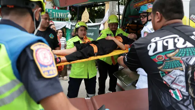 緊急救援人員在泰國曼谷郊外暖武里府挽粿縣（Bang Kruai）的帖詩琳暖武里學校將一名受傷教師抬上救護車（7/8/2026）