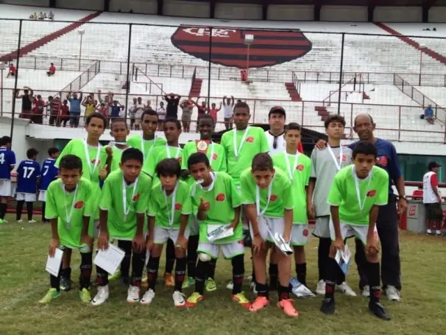 Um grupo de crianças usando uniforme verde. Vini Jr está na fileira de cima