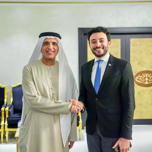 José Basila, con traje y corbata, junto a un diplomático árabe, dándose la mano.