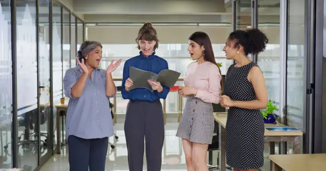 European happy young adult business woman lady standing look file paper read job promotion good news enjoy lucky day time old senior boss lady teen girl staff worker group team clap hands together office work place -