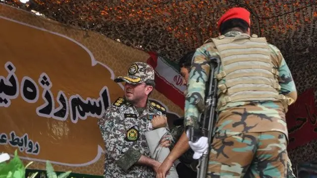 جایگاه سخنرانی مقام ها در رژه. نیروهای مسلح دست یک روحانی را برای نجات او گرفته اند