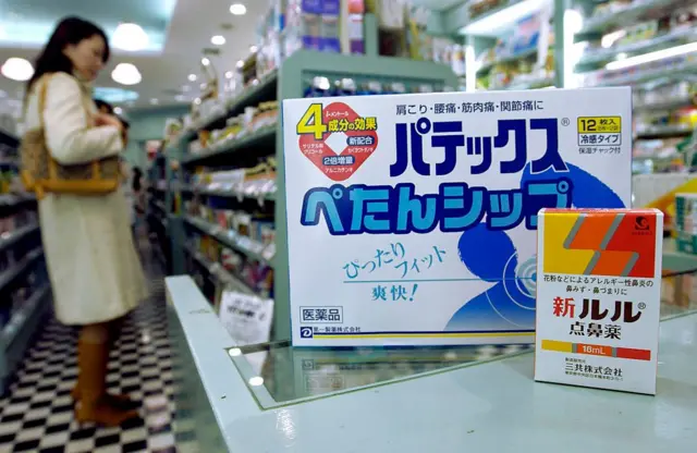 Una mujer en una farmacia y en el mostrador un remedio contra las alergias.