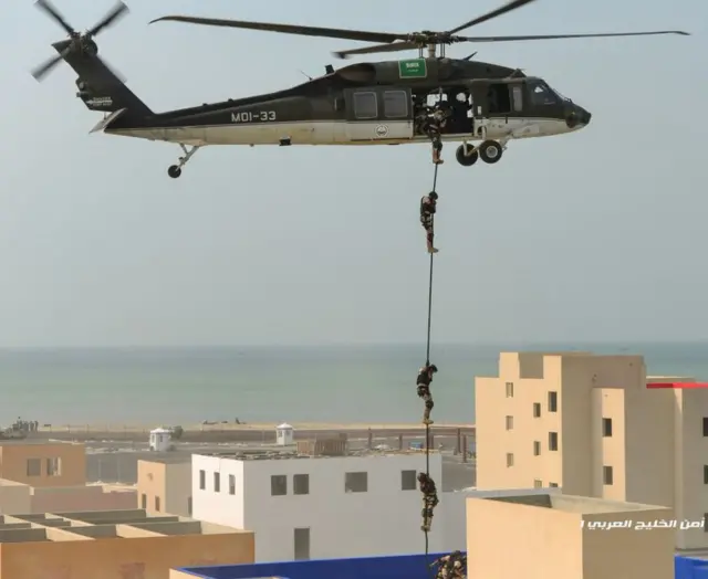 security agents shimmy down a rope from a helicopter to land on a rooftop
