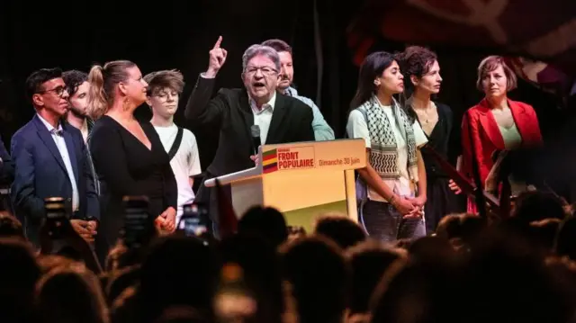 Jean-Luc Melenchon (C) gestures as he addresses a speech next to LFI party members