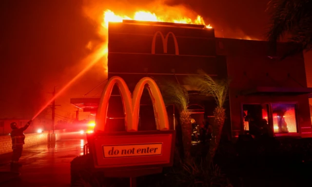 McDonald's şubesi yanıyor, gece alevler nedeniyle kızıl olmuş ve itfaiyeci söndürmeye çalışıyor