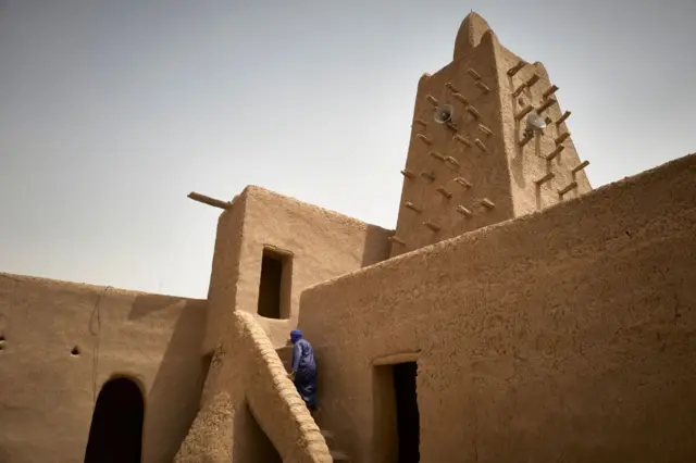 Un homme se dirige vers le toit de la mosquée Djinguereber à Tombouctou le 31 mars 2021.
