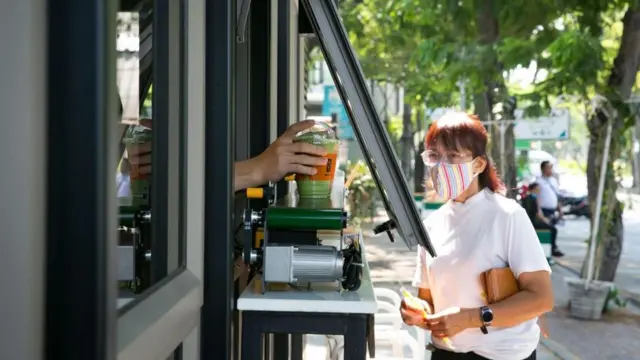 امرأة تشتري مشروبا بينما ترتدي كمامة