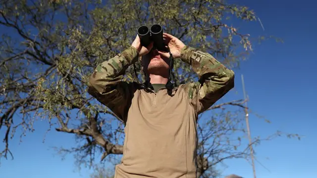 Paramilitar observa fronteira com México no Arizona com binóculo