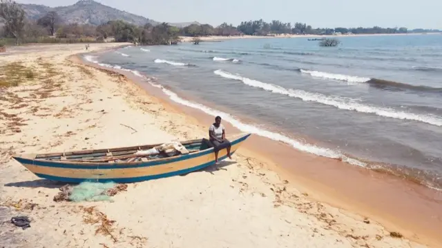 Georgina sentadaaposta blaze copa do mundoum barco diante do Lago Malawi