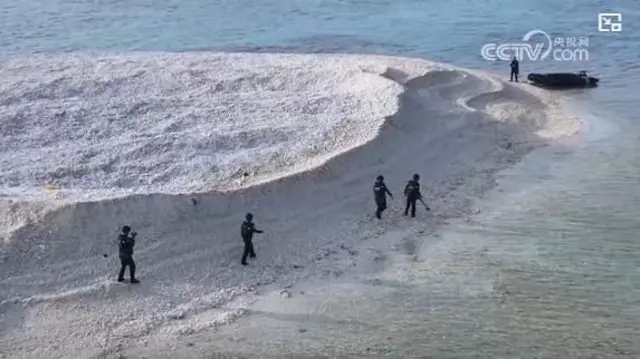 中国国営メディアは、サンディー礁を歩く海警局職員の様子を報じた