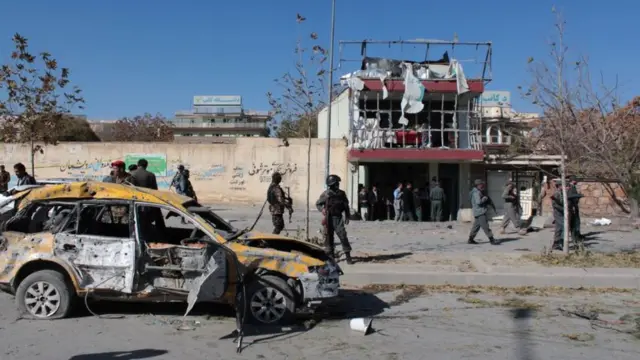 Badly damaged car in front of a building after a blast