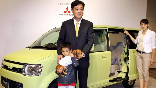 不正操作の対象となった「eKワゴン」の前でポーズをとる三菱自動車の益子会長