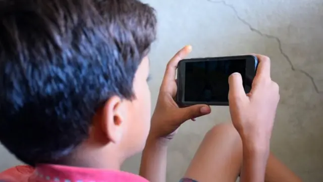 लहान मुलगा मोबाईल बघत असताना