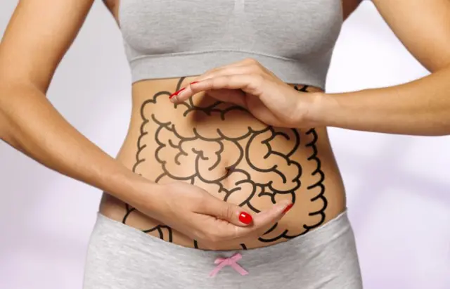 mulher mostra a barriga com intestino desenhado nela