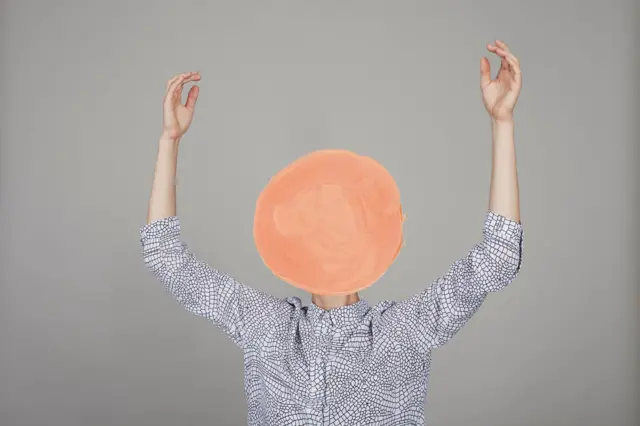 Imagen de una persona con la cabeza escondida por una ilustración de un círculo pintado a mano 