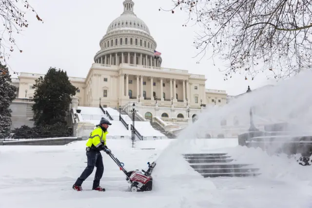 службено лице чисти снег уз помоћ машине за чишћење снега испред зграде Капитола у Вашингтону 
