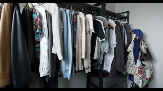 照片中是一排整齊懸掛的衣物，包括T恤、外套、包包與帽子。