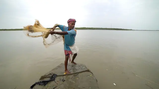 Pescador lanzando redes en el mar den Sundarbans