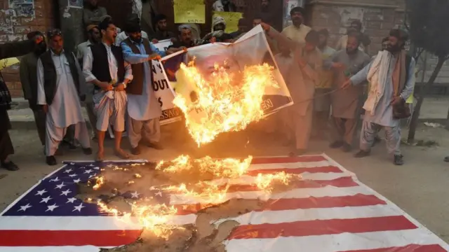 Pakistaníes protestan quemando la foto de Donald Trump y la bandera de EE.UU. por un bombardeo estadounidense en la ciudad afgana de Quetta.